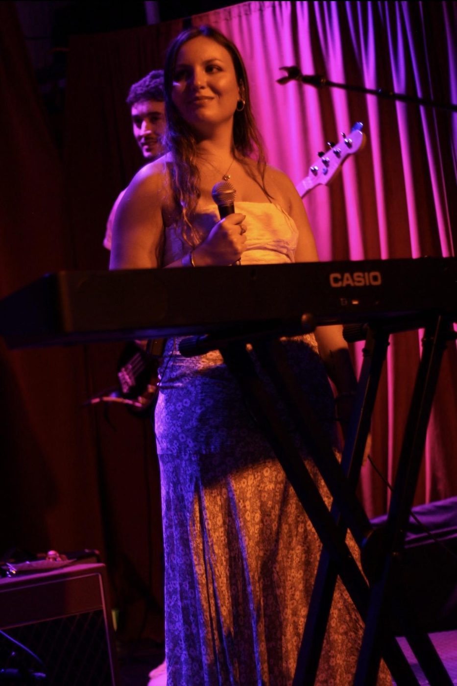 Bella singing at a keyboard under purple stage lights